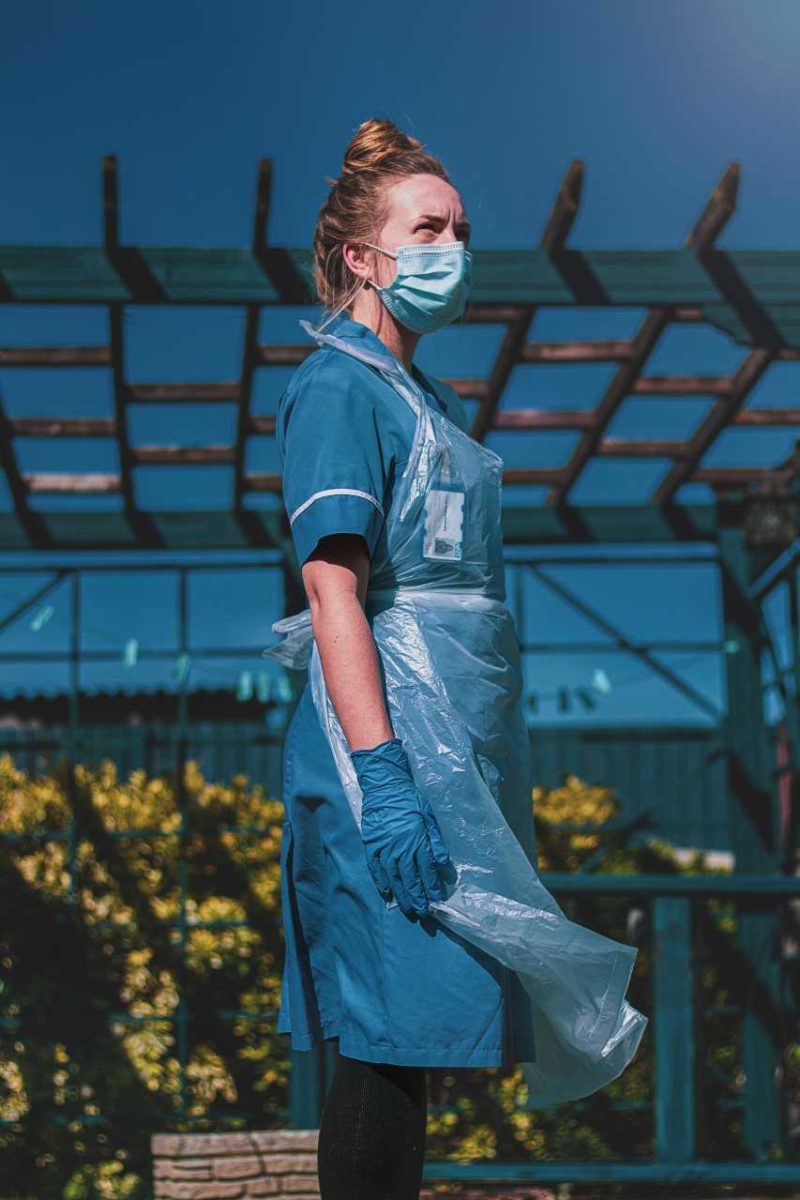 Nurse looking into the distance, wearing scrubs and a facemask