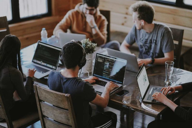 Group of students sat around a table all using laptops