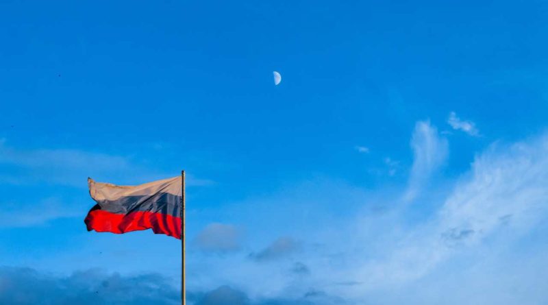 Russian flag on a flagpole set against a blue sky