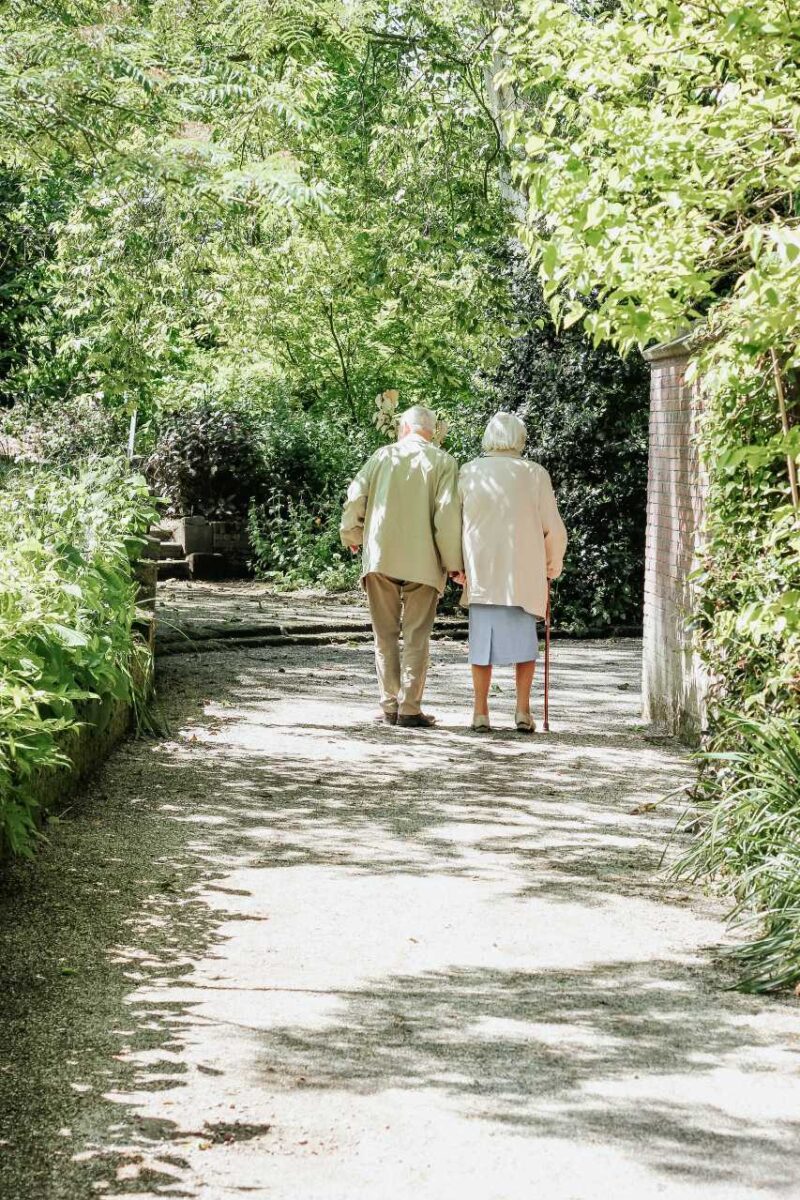An older couple walking down a tree-lined path