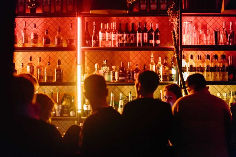 Group of people stood at a busy, dimly-lit bar