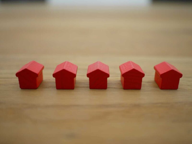 A row of red model houses on a wooden table