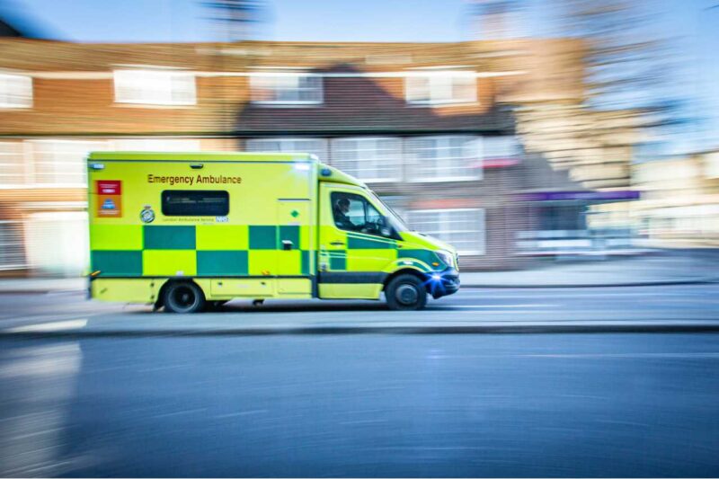 Ambulance travelling at speed with a blurred background of a street