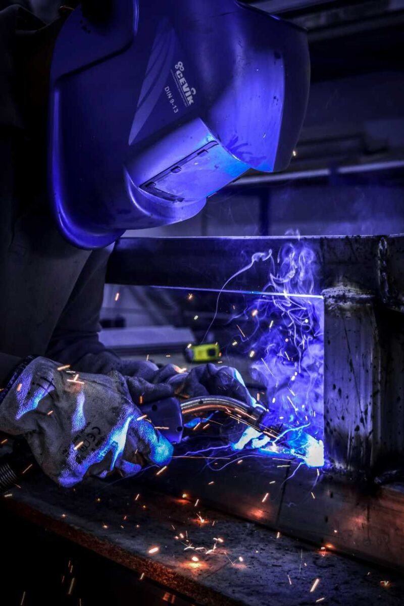 Person wearing a welding mask with sparks flying from the welding
