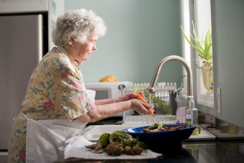 A woman washing a carrot in the sink